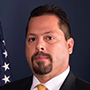a man in a suit and tie in front of an american flag